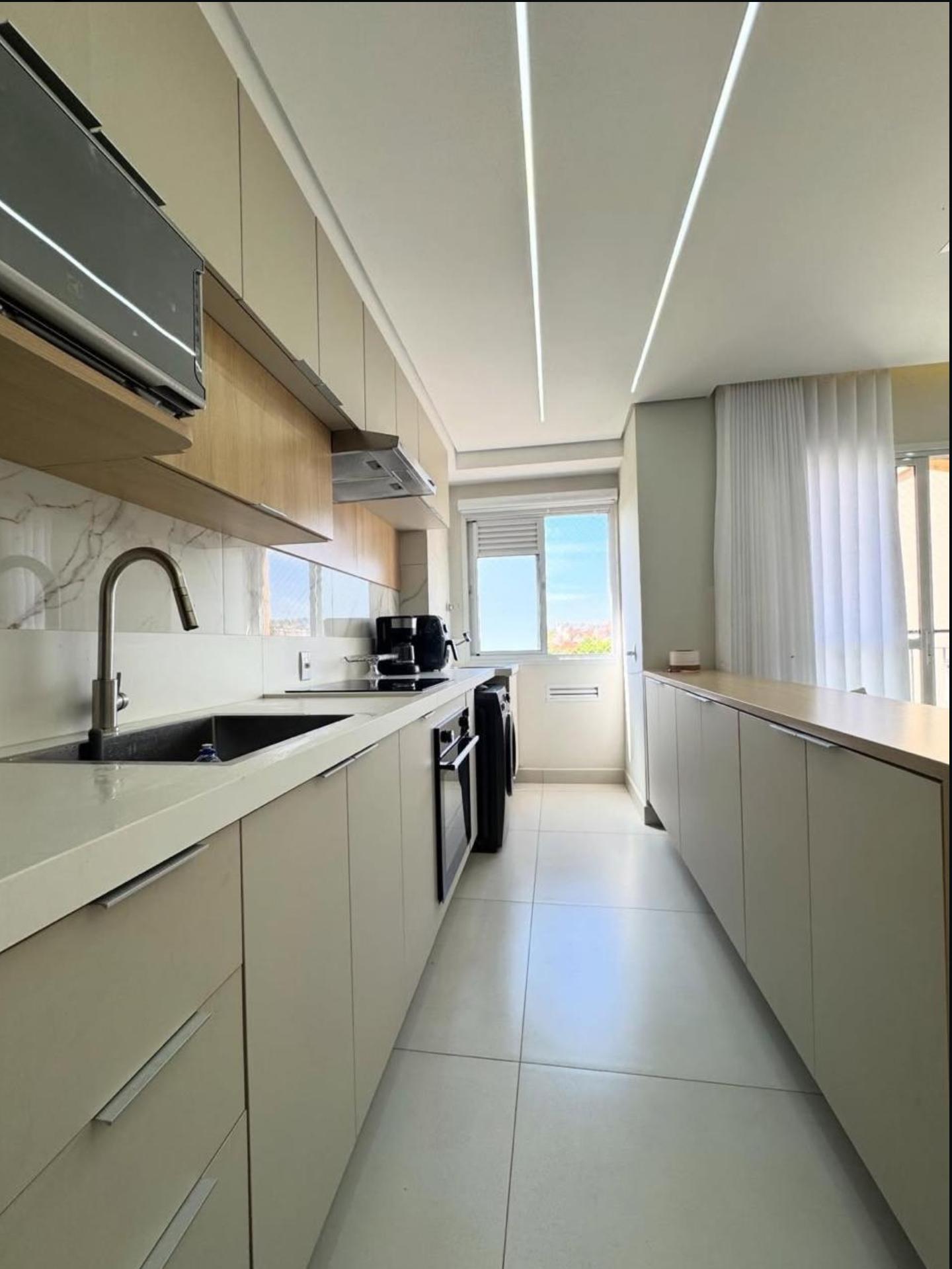 Cozinha corredor com armários bege e iluminação LED