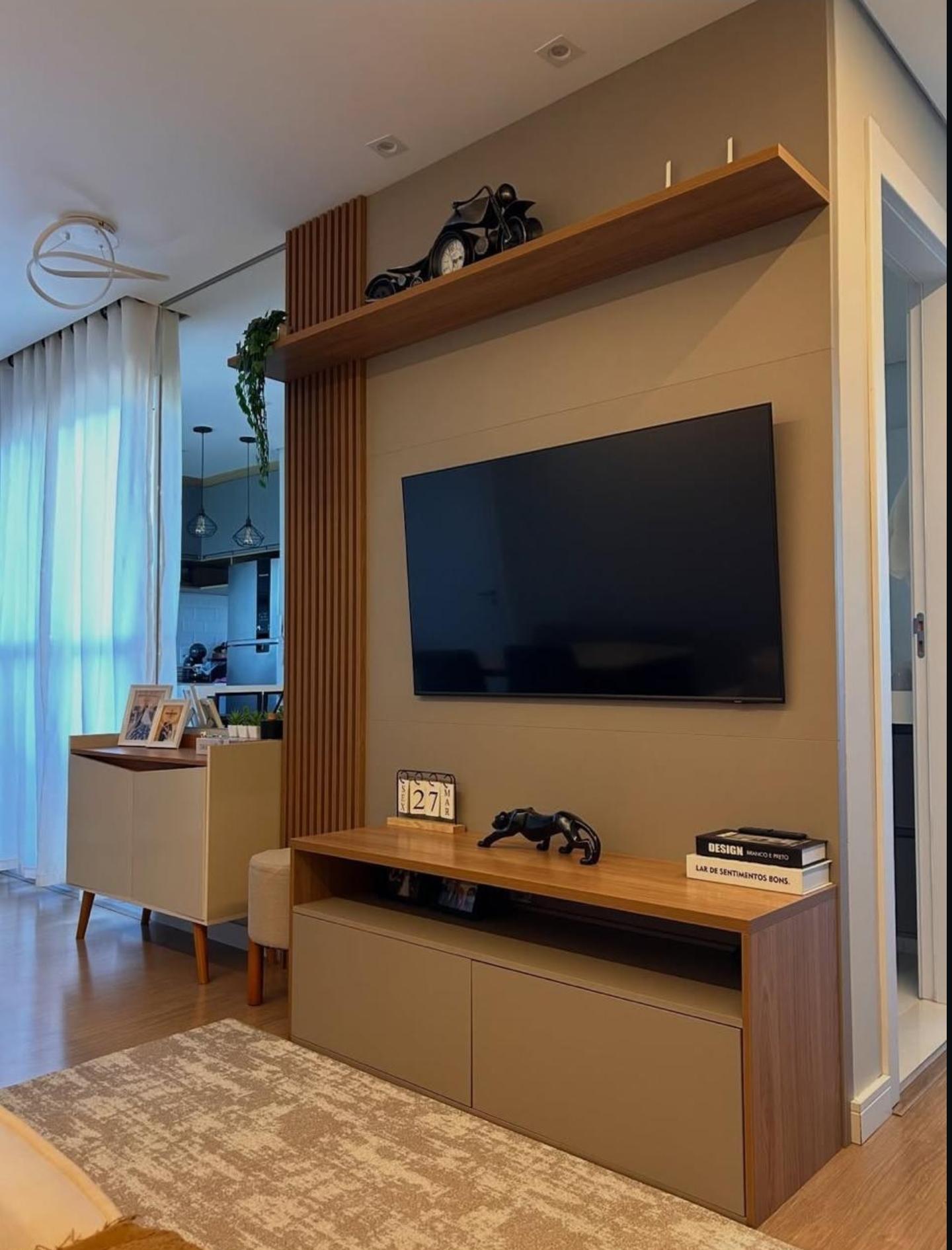 Sala de estar com painel de TV em madeira e rack suspenso