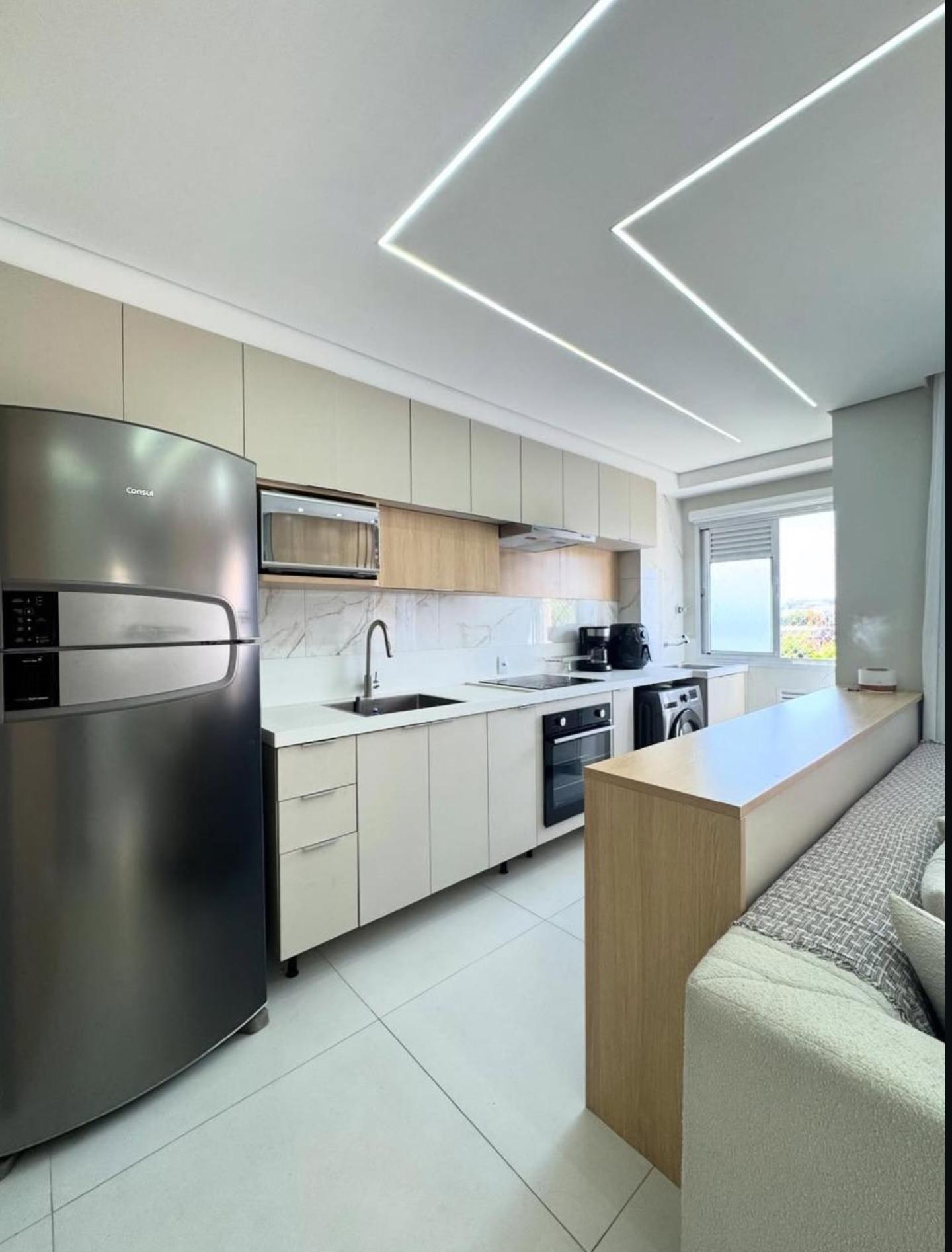 Cozinha integrada com armários bege e iluminação LED no teto