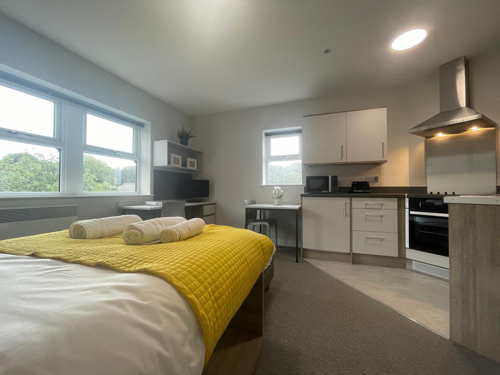 Studio unit with yellow bed and kitchenette