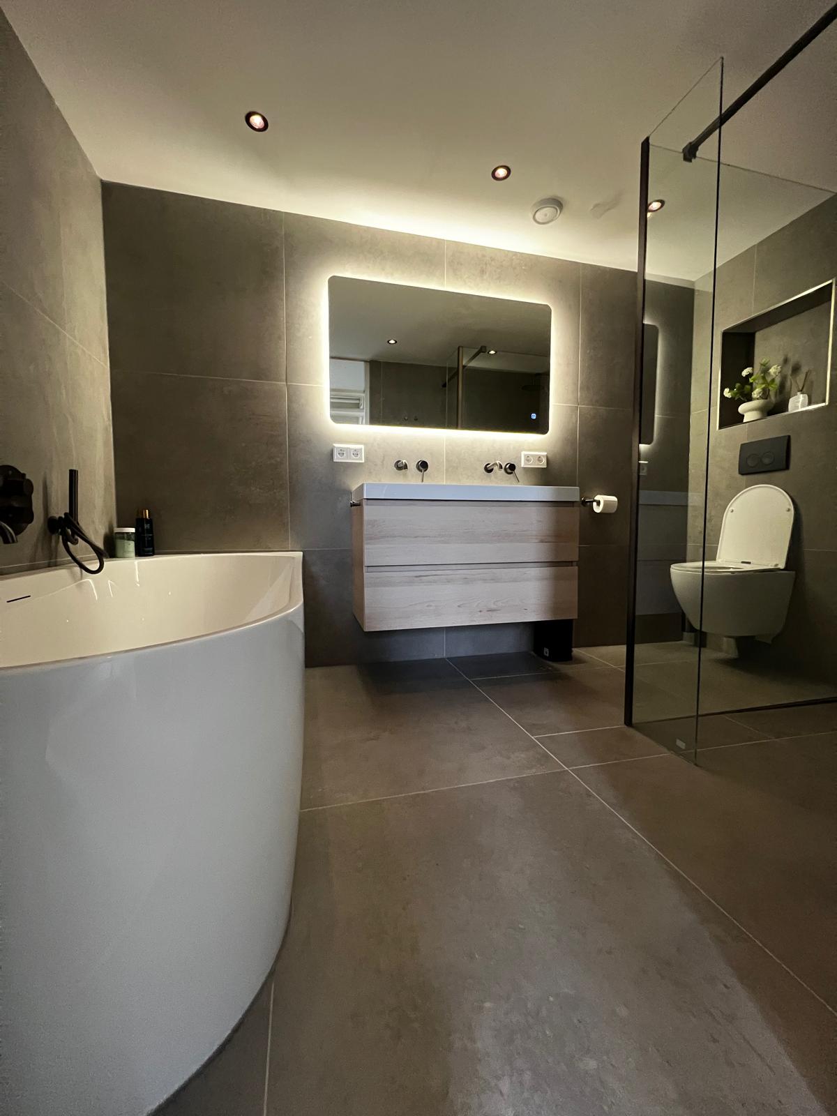 Moderne badkamer met vrijstaand bad, glazen douchecabine en verlichte spiegel