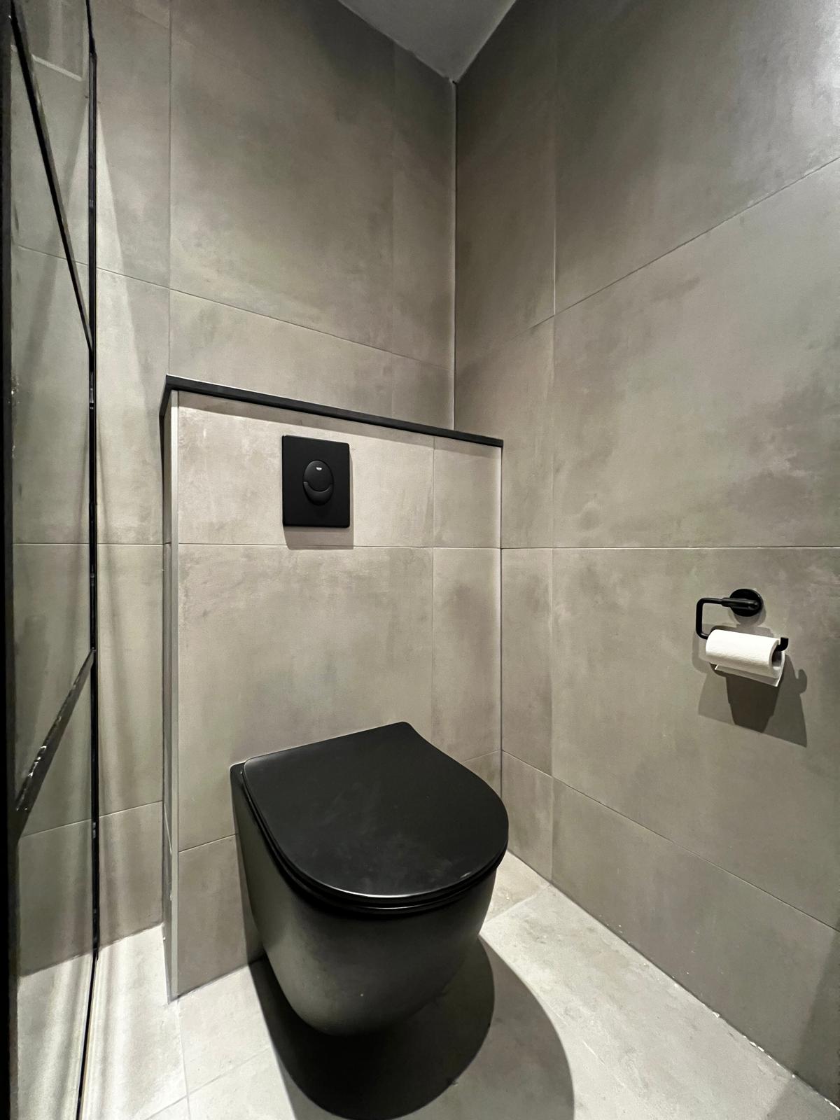 Toilet met beton-look grijze tegels en zwart hangend toilet