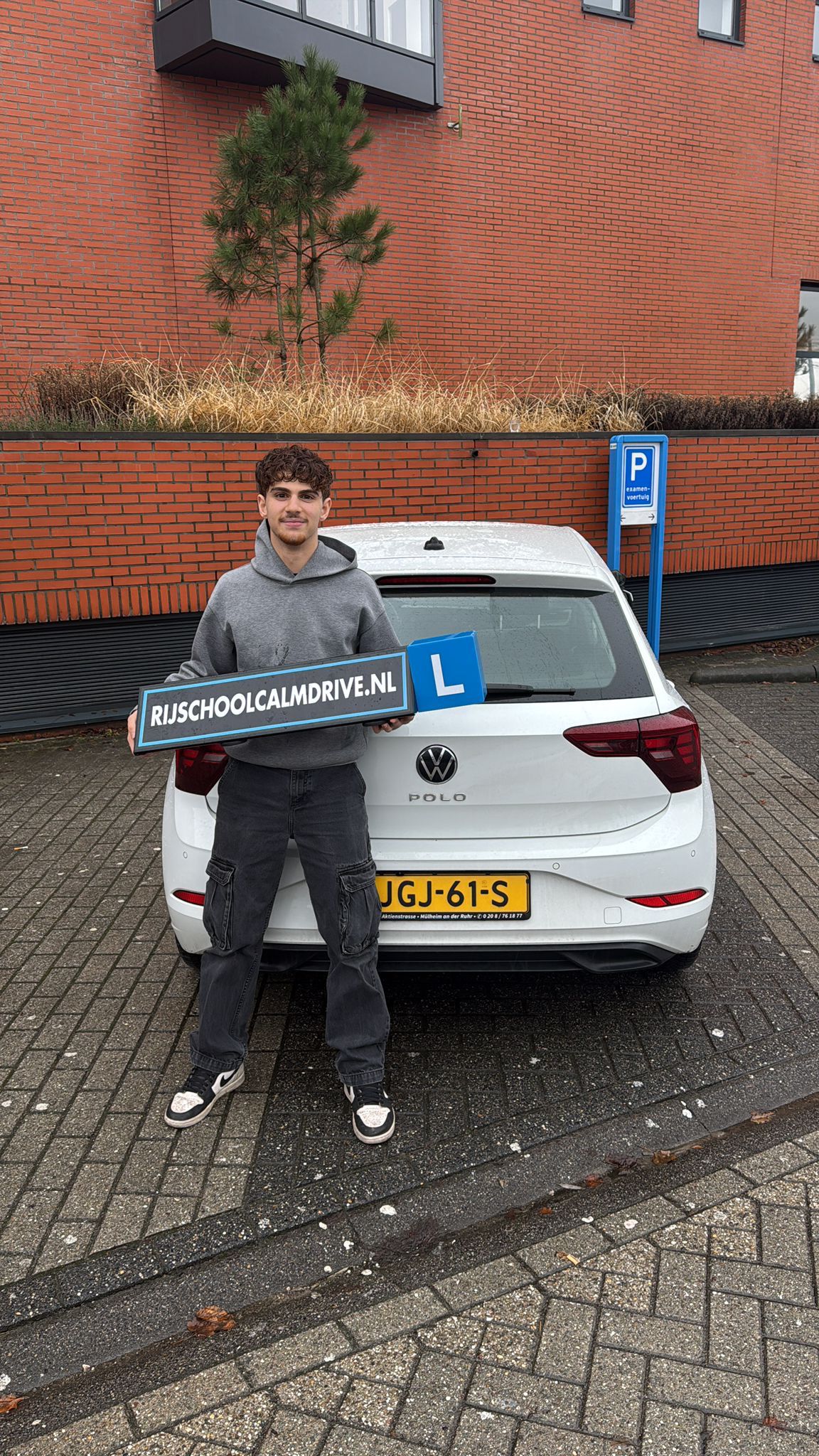 Geslaagde leerling bij witte Calm Drive lesauto
