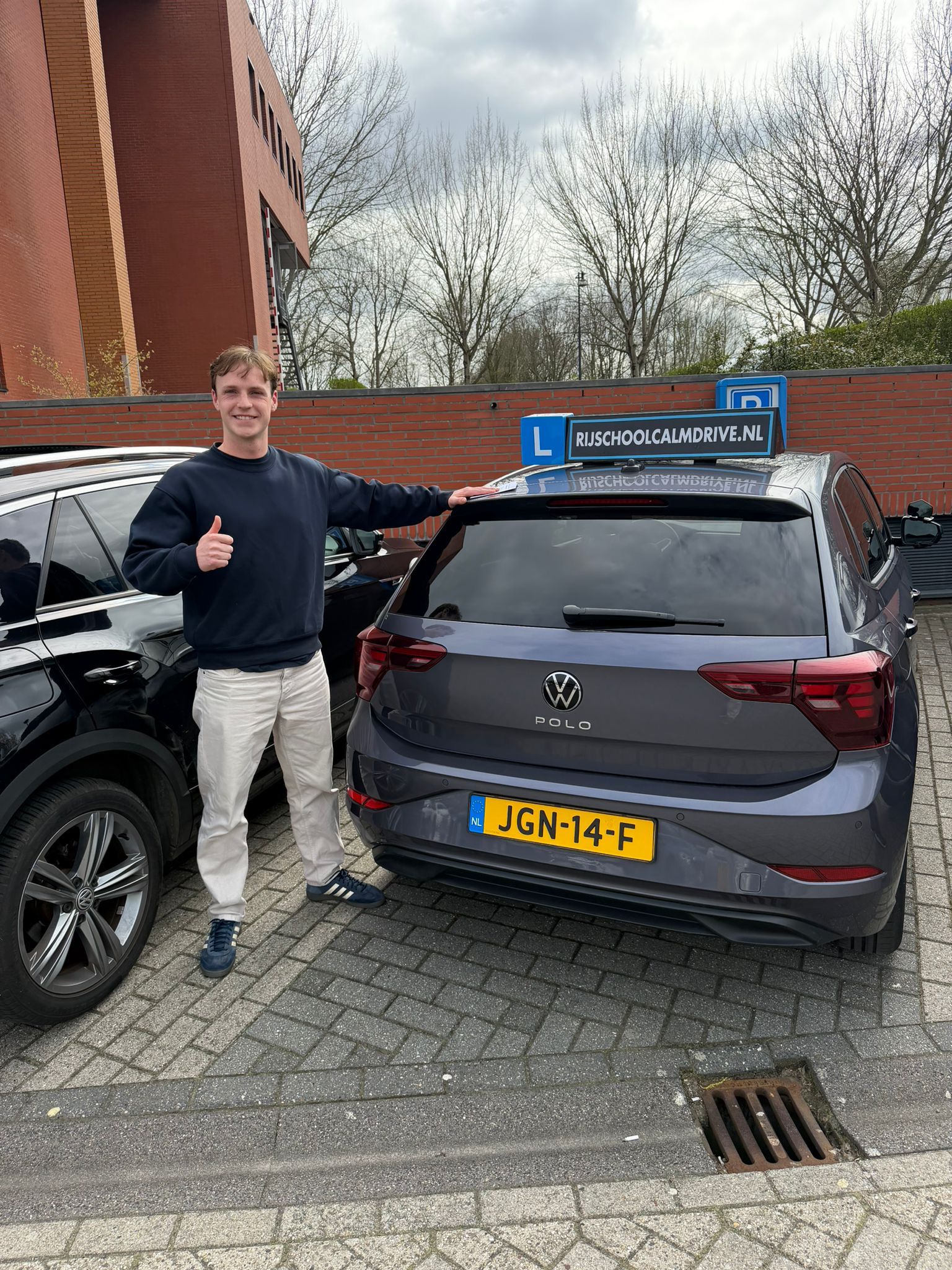 Geslaagde leerling bij grijze Calm Drive lesauto