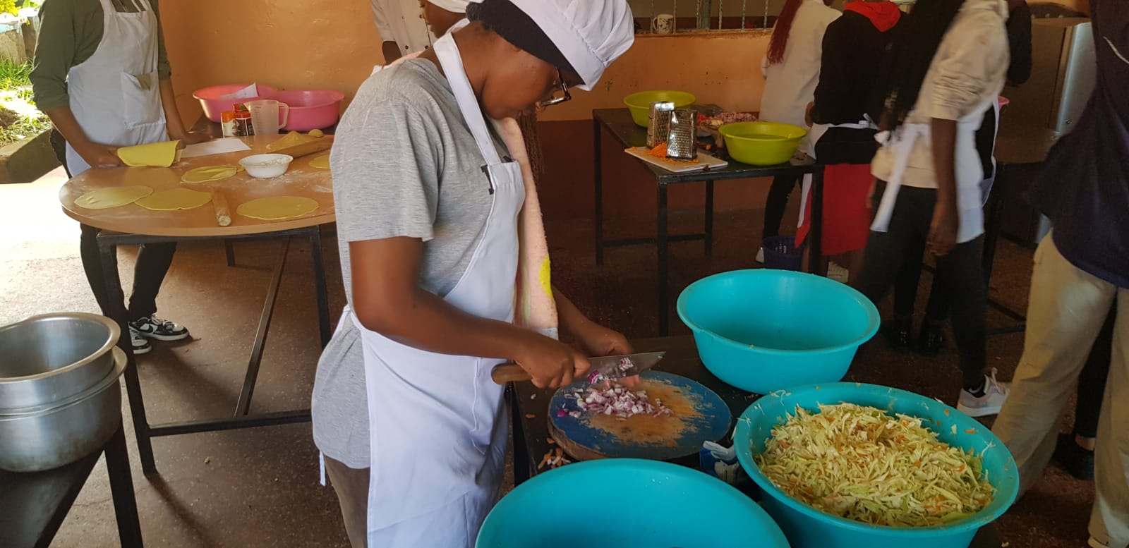 Food production student in chef's hat chopping onions during a cookery practical