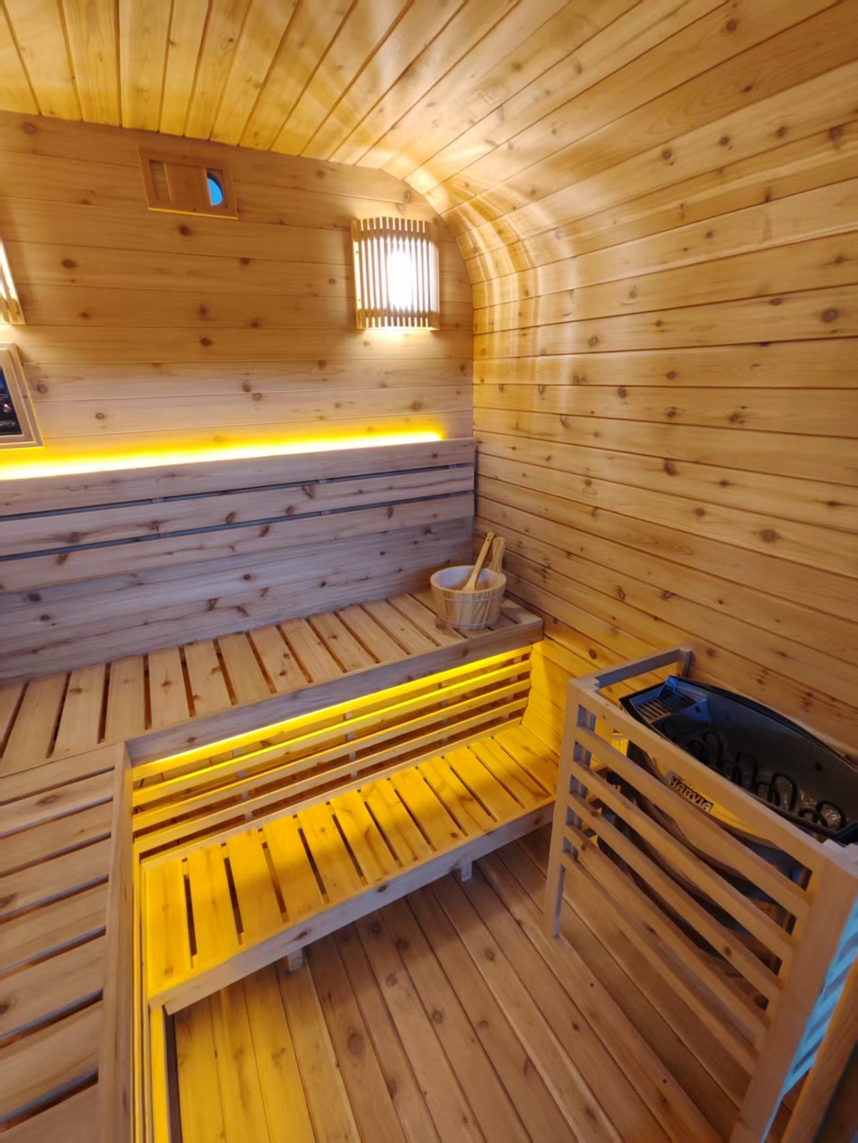 Finished cedar interior with two-tier seating, backrest wall lighting and the Harvia electric heater in its timber guard