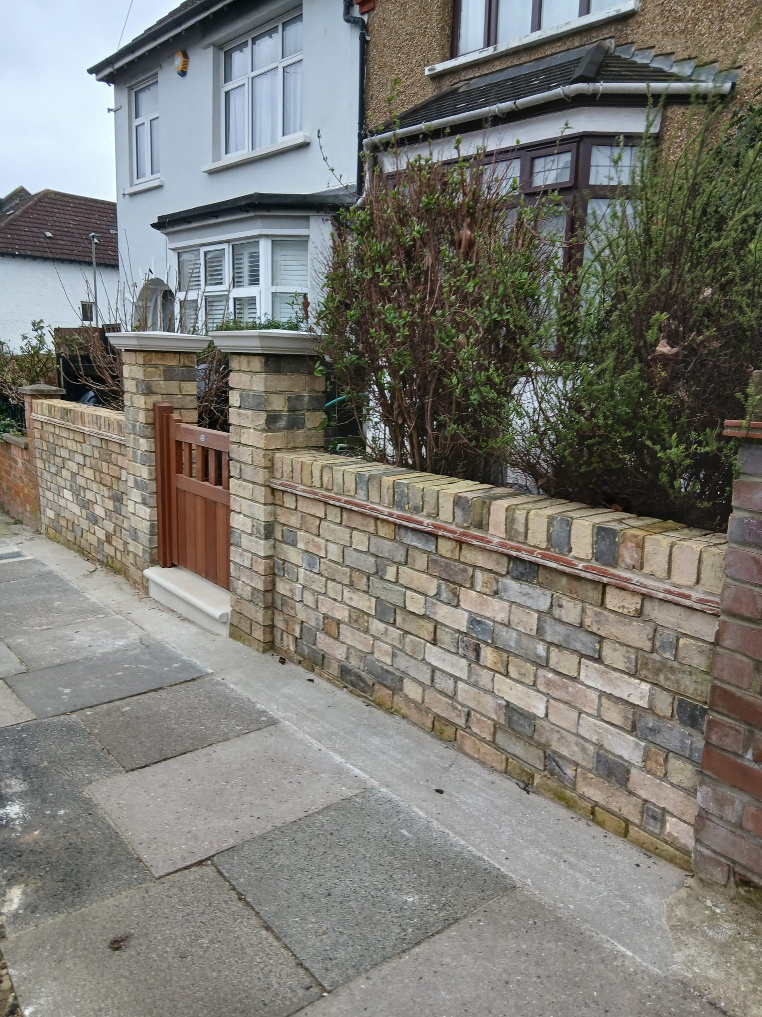 Front garden boundary in reclaimed yellow stock brick with brick piers, stone coping and a wooden pedestrian gate