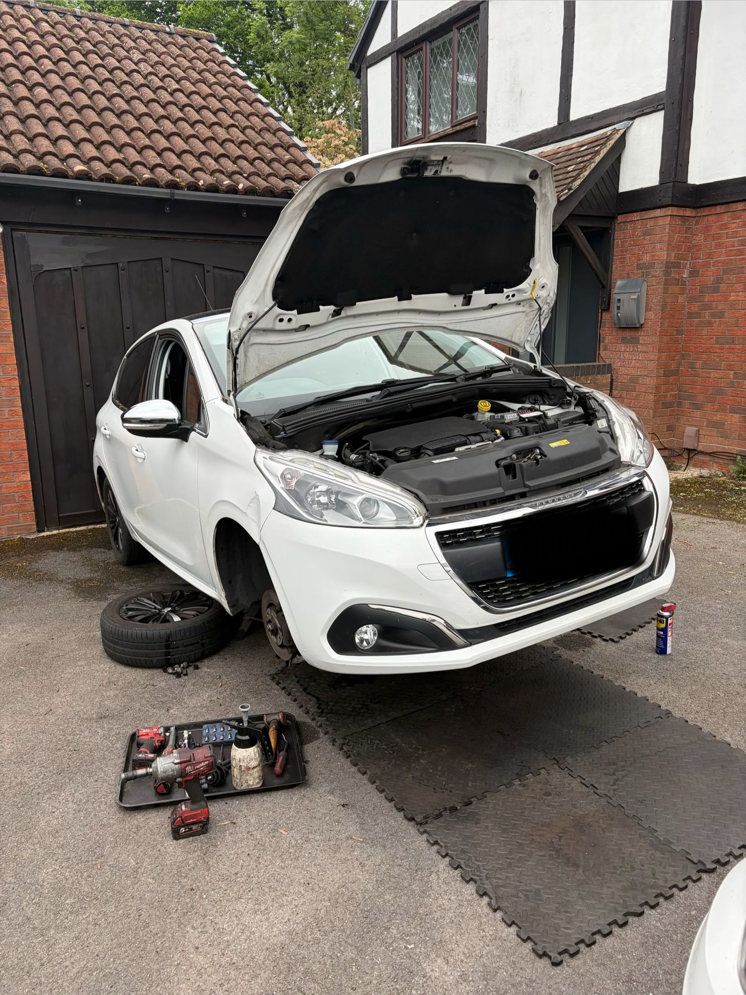SMART Mobile Mechanic performing clutch replacement on white Peugeot 208 at customer's home driveway