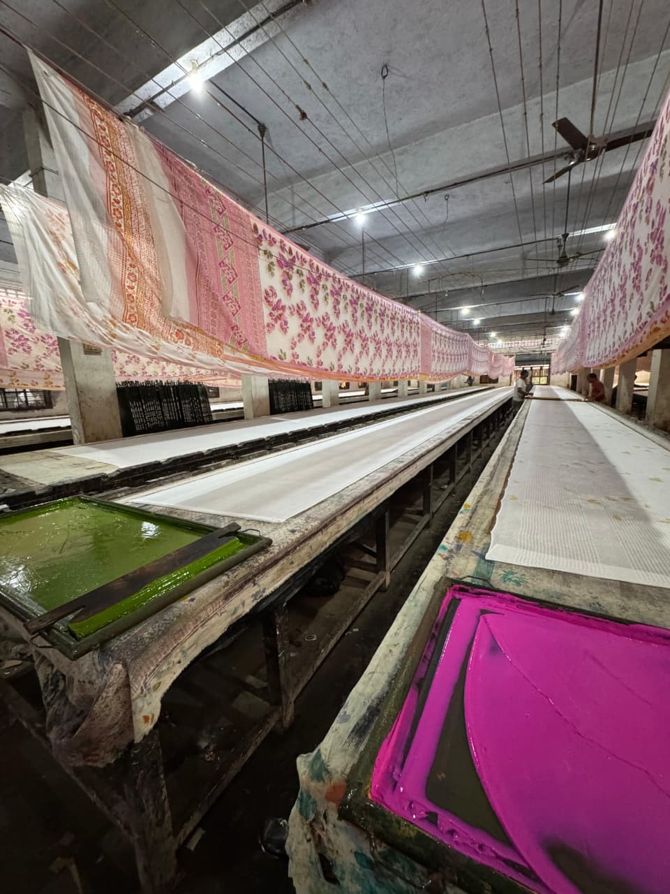 Long printing tables with sarees drying overhead and pigment trays at A-1 Prints factory