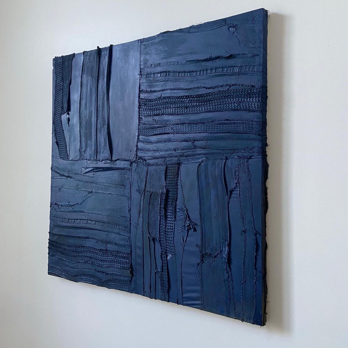 Monochromatic deep navy blue textured abstract with embedded fabric and mixed media in a grid composition