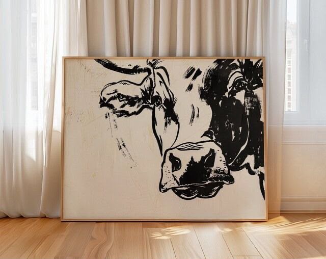Bold gestural black ink-style cow portrait taking up most of the canvas against a raw cream ivory textured background, framed in oak