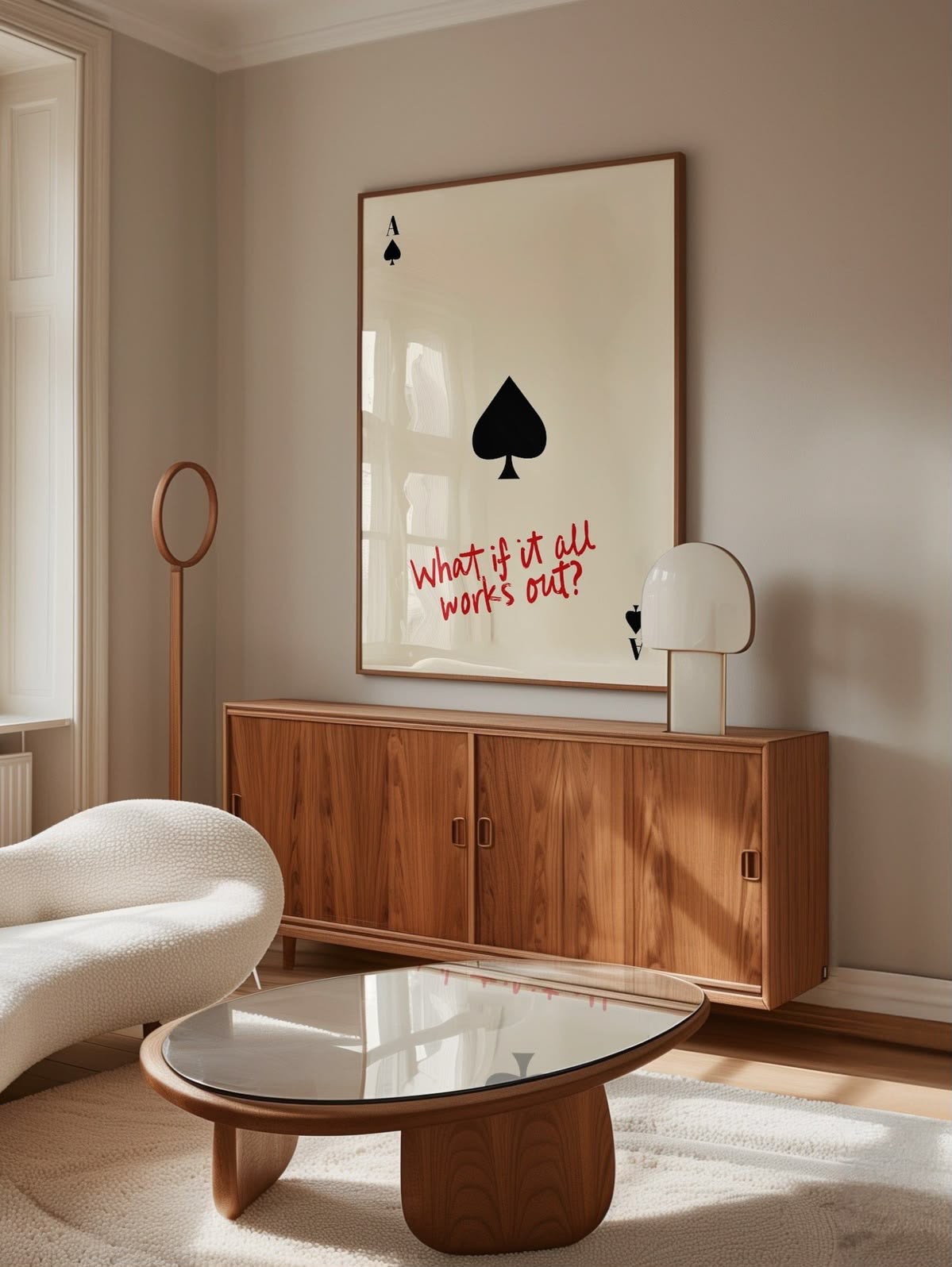 Ace of Spades playing card on cream with red handwritten text reading 'What if it all works out?' framed and displayed above a walnut credenza