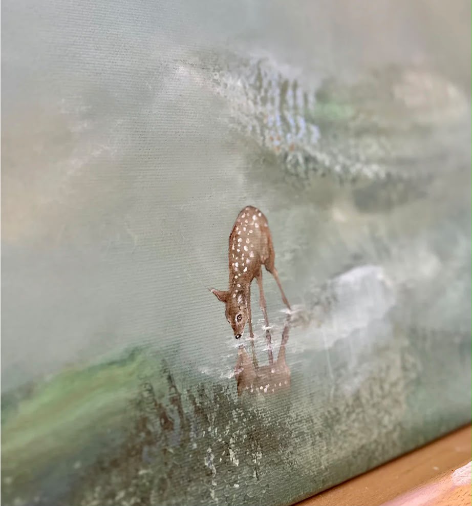 Close-up detail of a spotted fawn drinking from still water with its reflection visible on a sage-green misty canvas