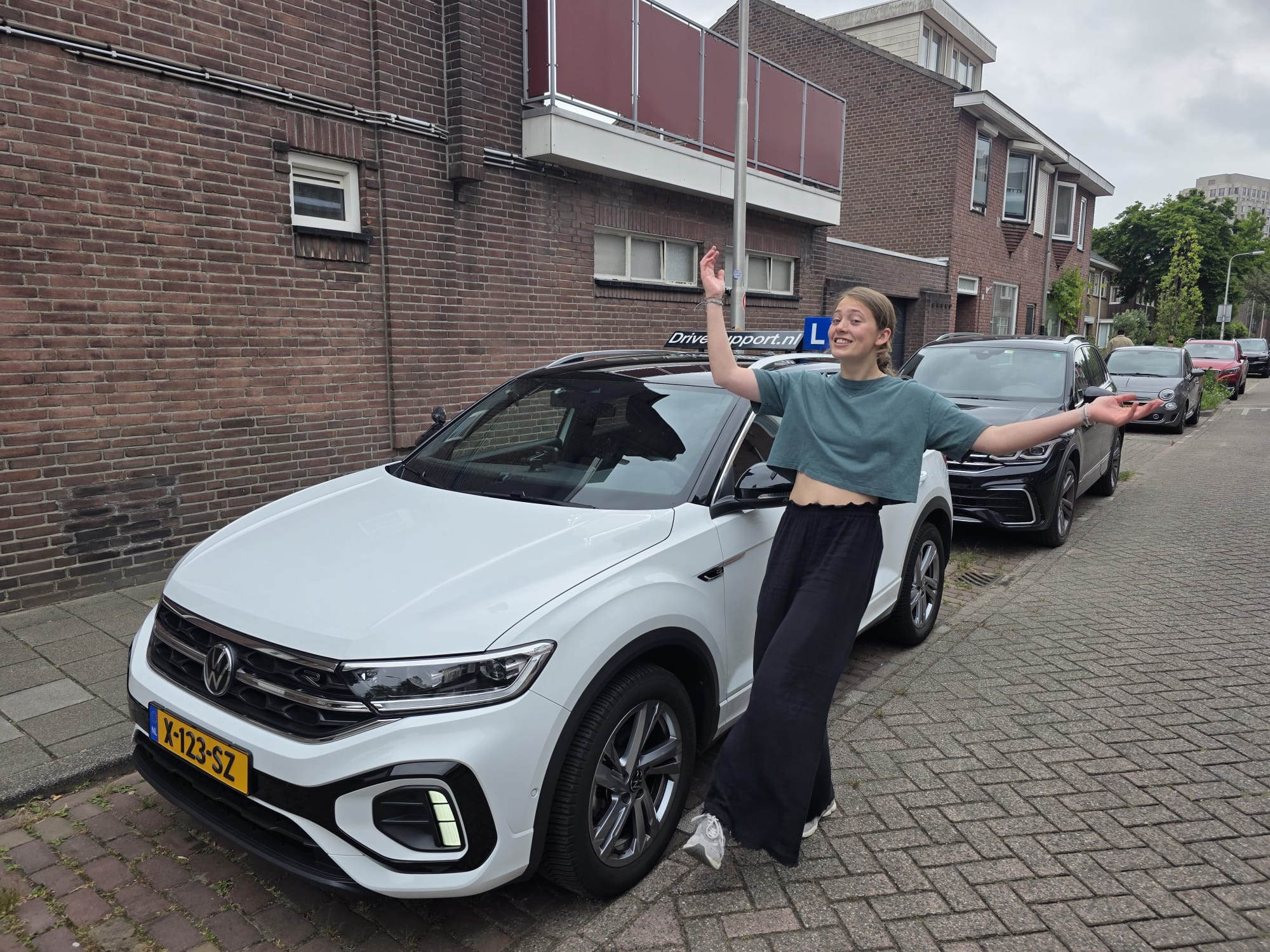 Tevreden leerling viert het slagen naast de DriveSupport lesauto in Tilburg