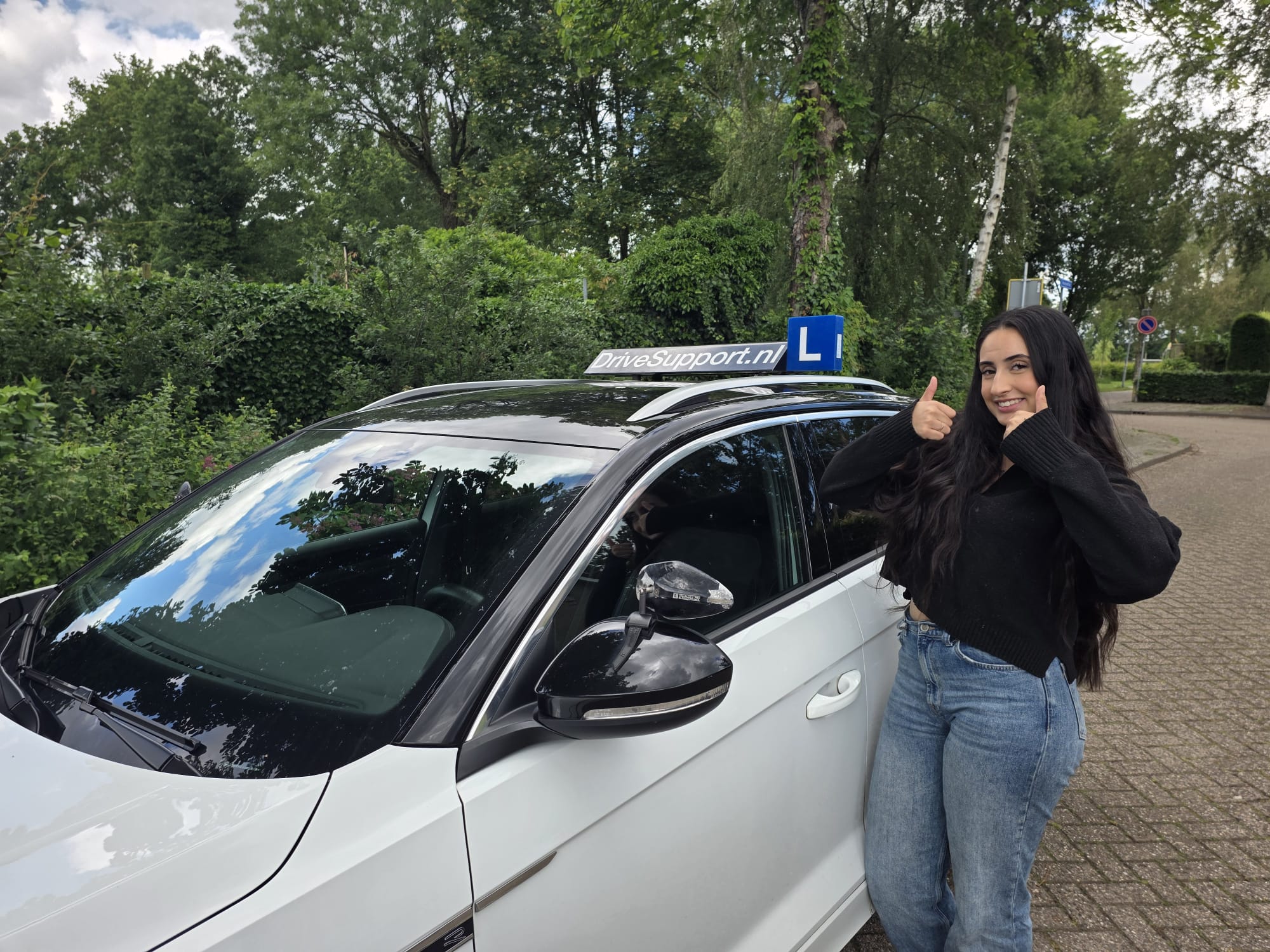 Geslaagde leerling naast DriveSupport lesauto bij groene weg Tilburg