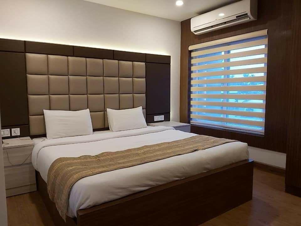 Luxury bedroom with zebra blinds on the window and a padded headboard by M.A Blinds & Curtains
