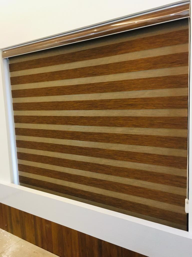 Warm wood-tone zebra roller blind installed over a wide window by M.A Blinds & Curtains