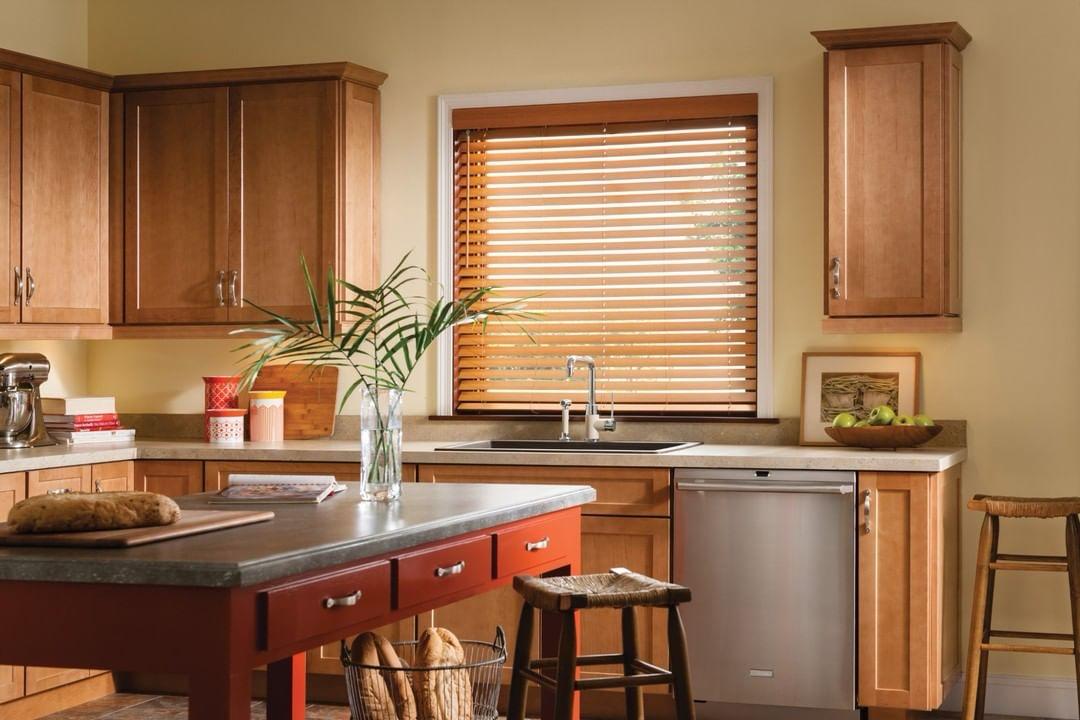 Wooden venetian blinds over a kitchen sink window with timber cabinetry by M.A Blinds & Curtains