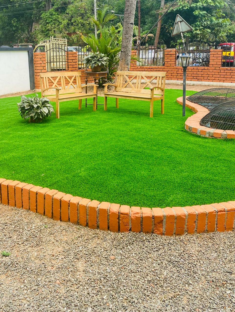 Manicured artificial grass lawn with brick edging and garden benches by M.A Blinds & Curtains