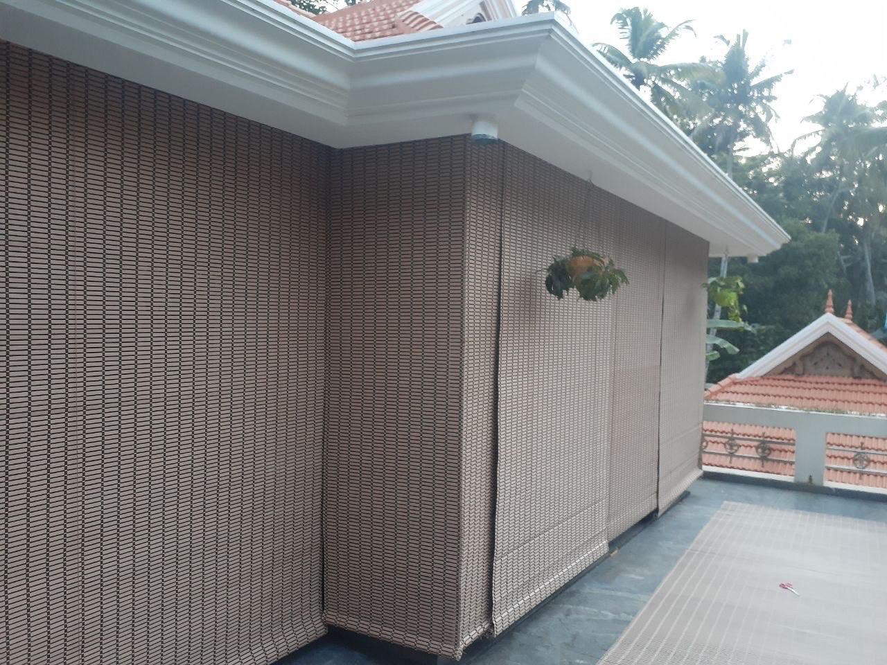 Woven bamboo-style outdoor roller blinds enclosing a terrace by M.A Blinds & Curtains