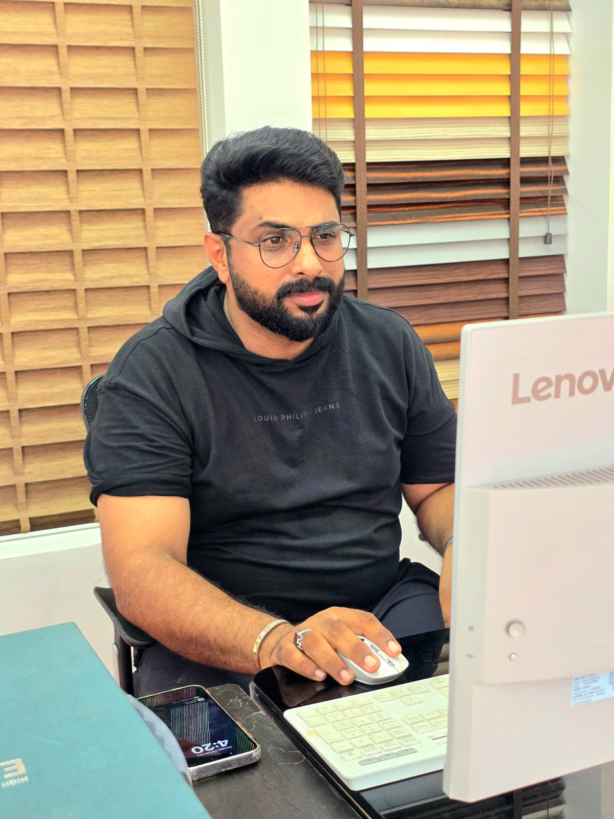 Shan Sathar, proprietor of M.A Blinds & Curtains, at his workspace showcasing wooden blind samples
