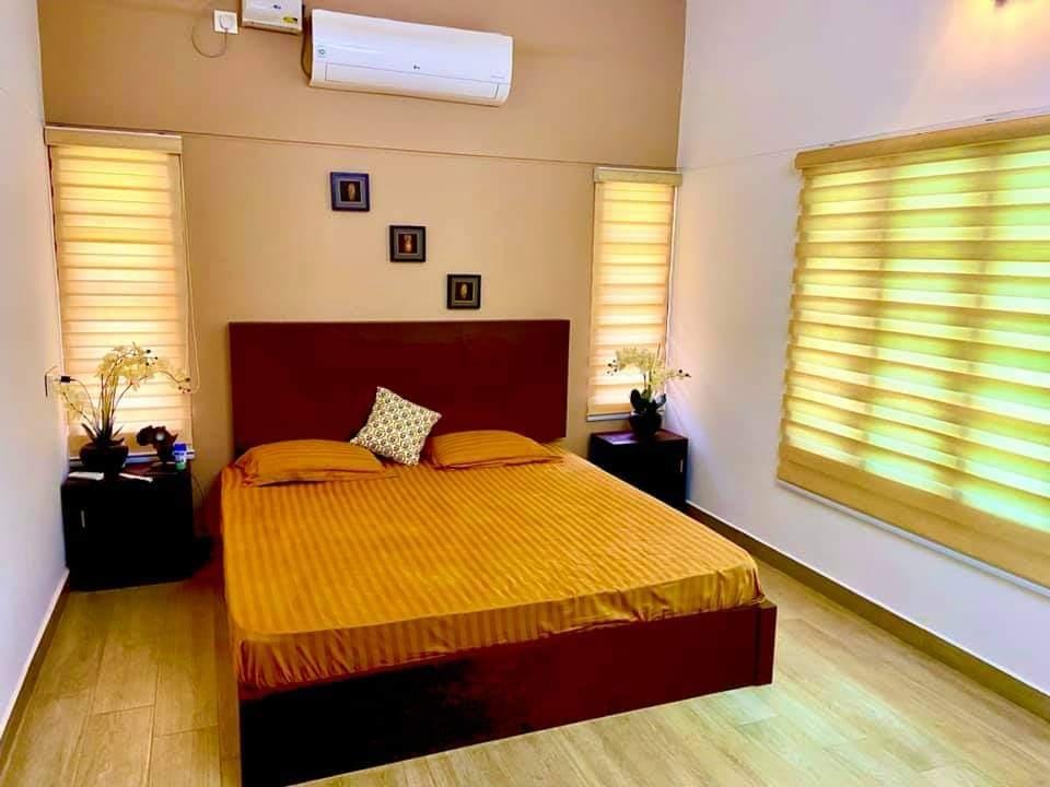 Bedroom with yellow and orange zebra blinds creating ambient lighting effects by M.A Blinds & Curtains