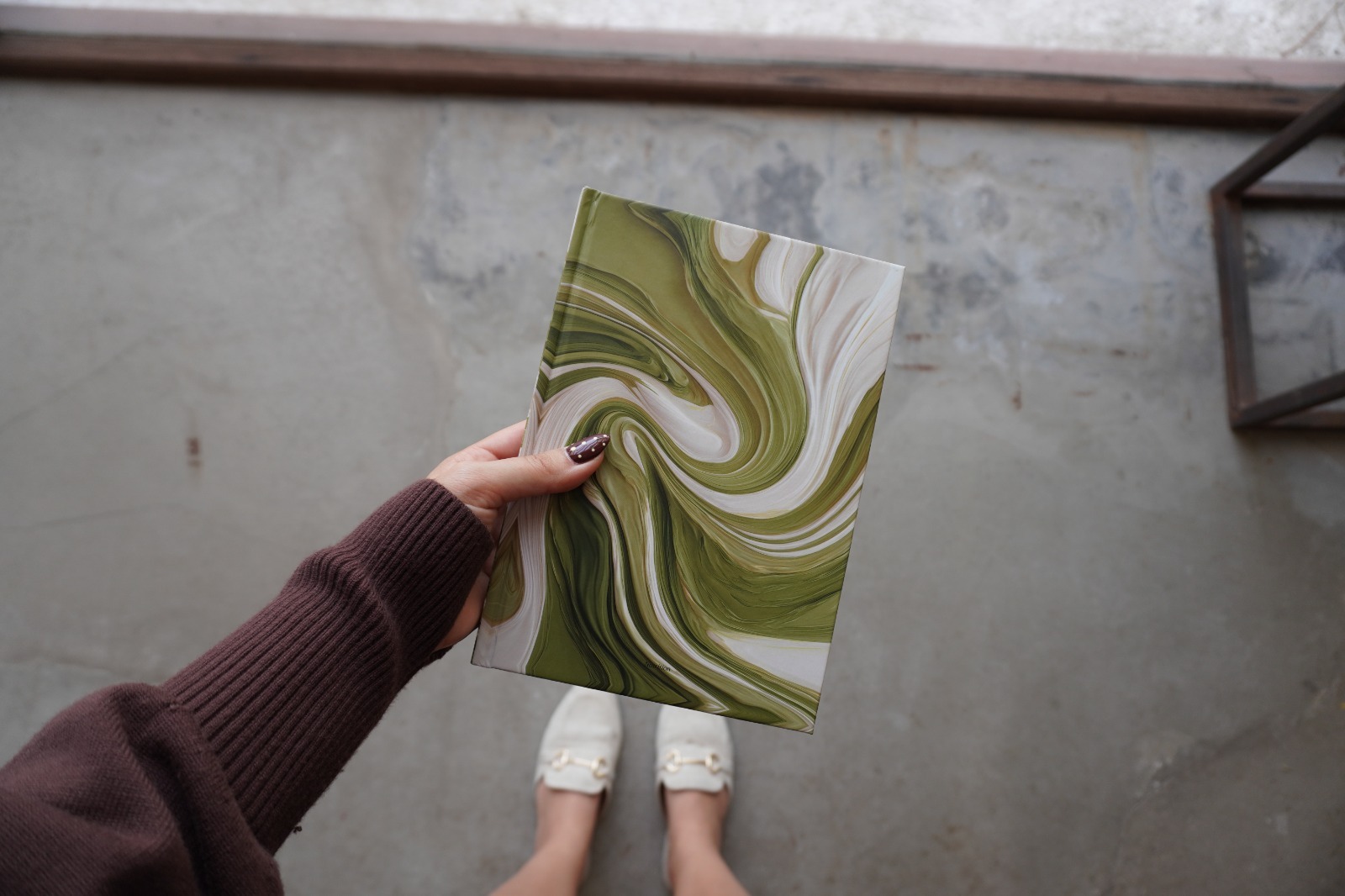 Green marble edition of The Natrition Method journal held against a warm-toned wall