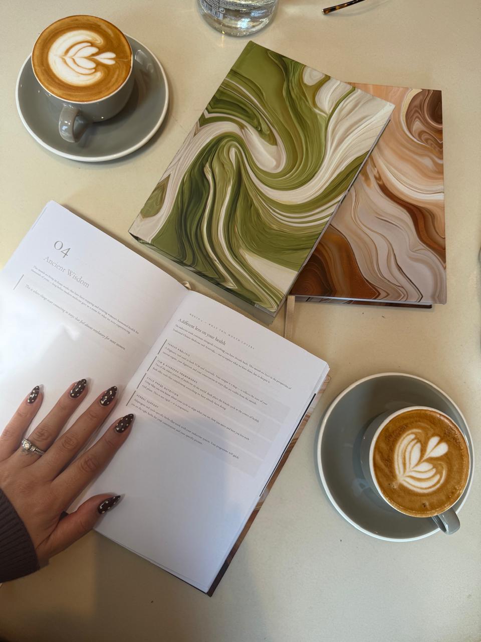 Both journal editions open to the Ancient Wisdom chapter with two coffees