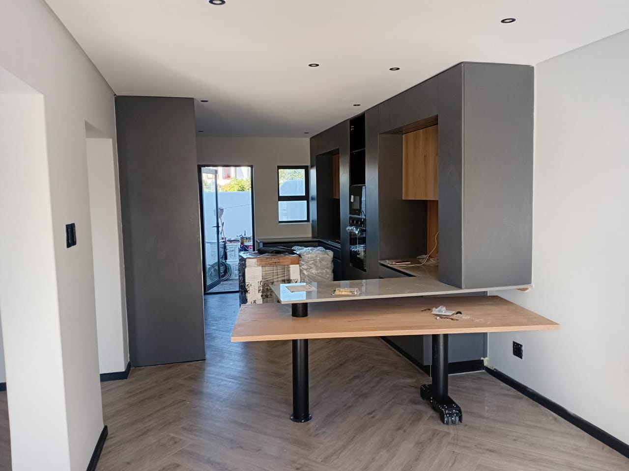 Interior painting Port Elizabeth — open plan with white walls, charcoal grey column and cabinetry, recessed downlights, island bench being installed