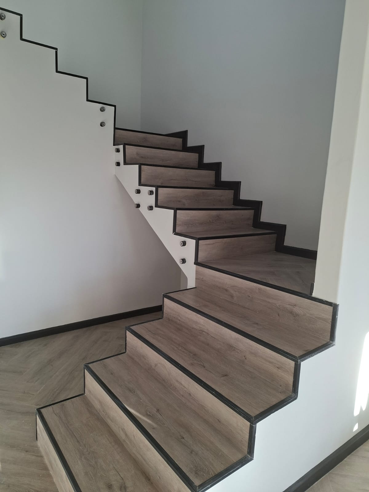 Interior painting Port Elizabeth — floating staircase full height view with timber vinyl treads, glass balustrade, white painted walls, herringbone floor