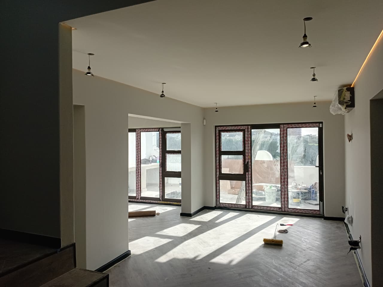 Interior painting Port Elizabeth — bright open plan with white walls, recessed downlights, two sets of large glazed folding doors to balcony