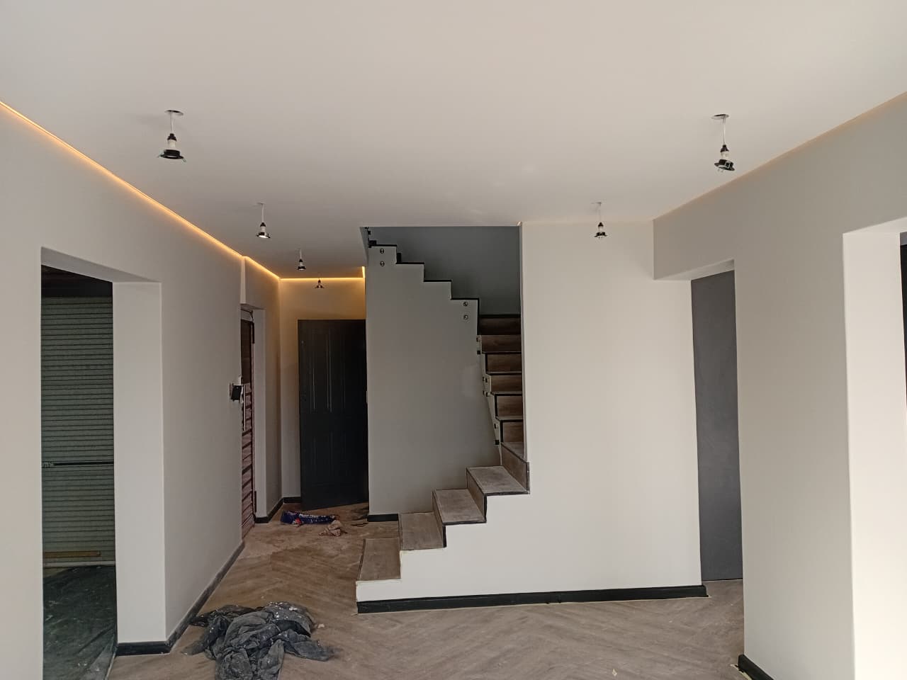 Interior painting Gqeberha — open plan hallway with white walls, recessed LED strip lighting on ceiling, floating staircase with glass balustrade
