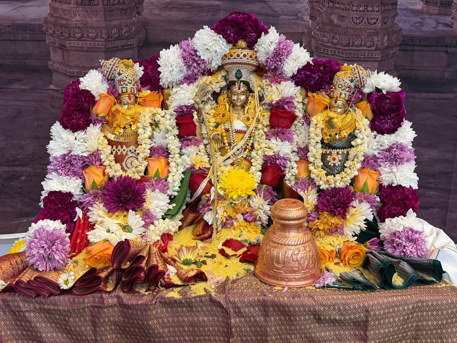 Colorful floral decoration surrounding Hindu deities for a pooja ceremony