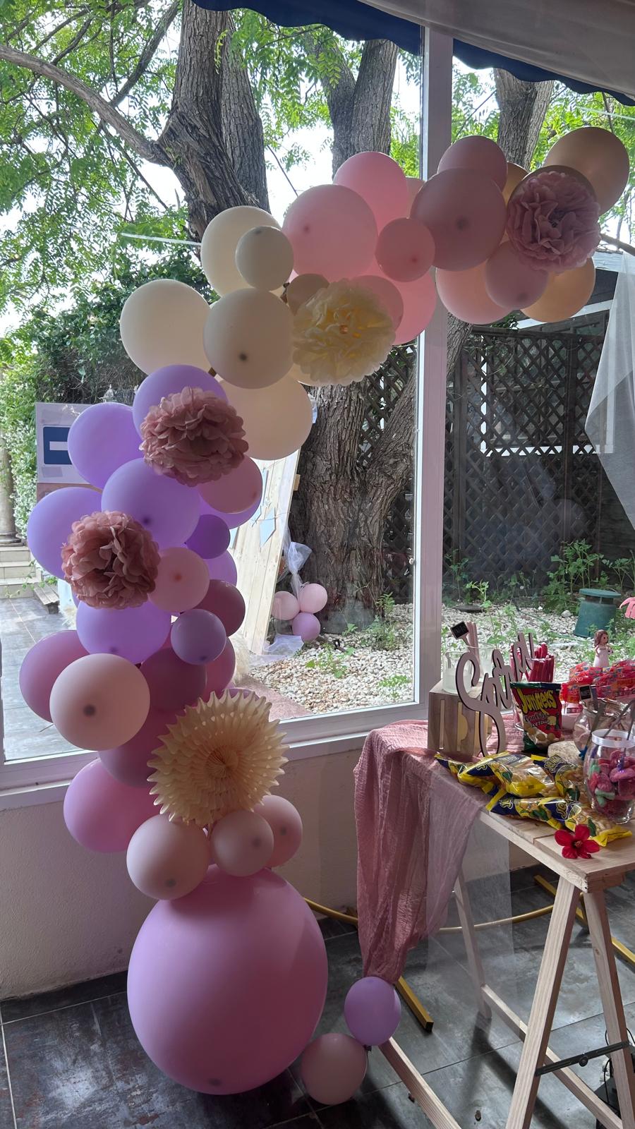 Arco de globos rosa morado con peonías en ventana