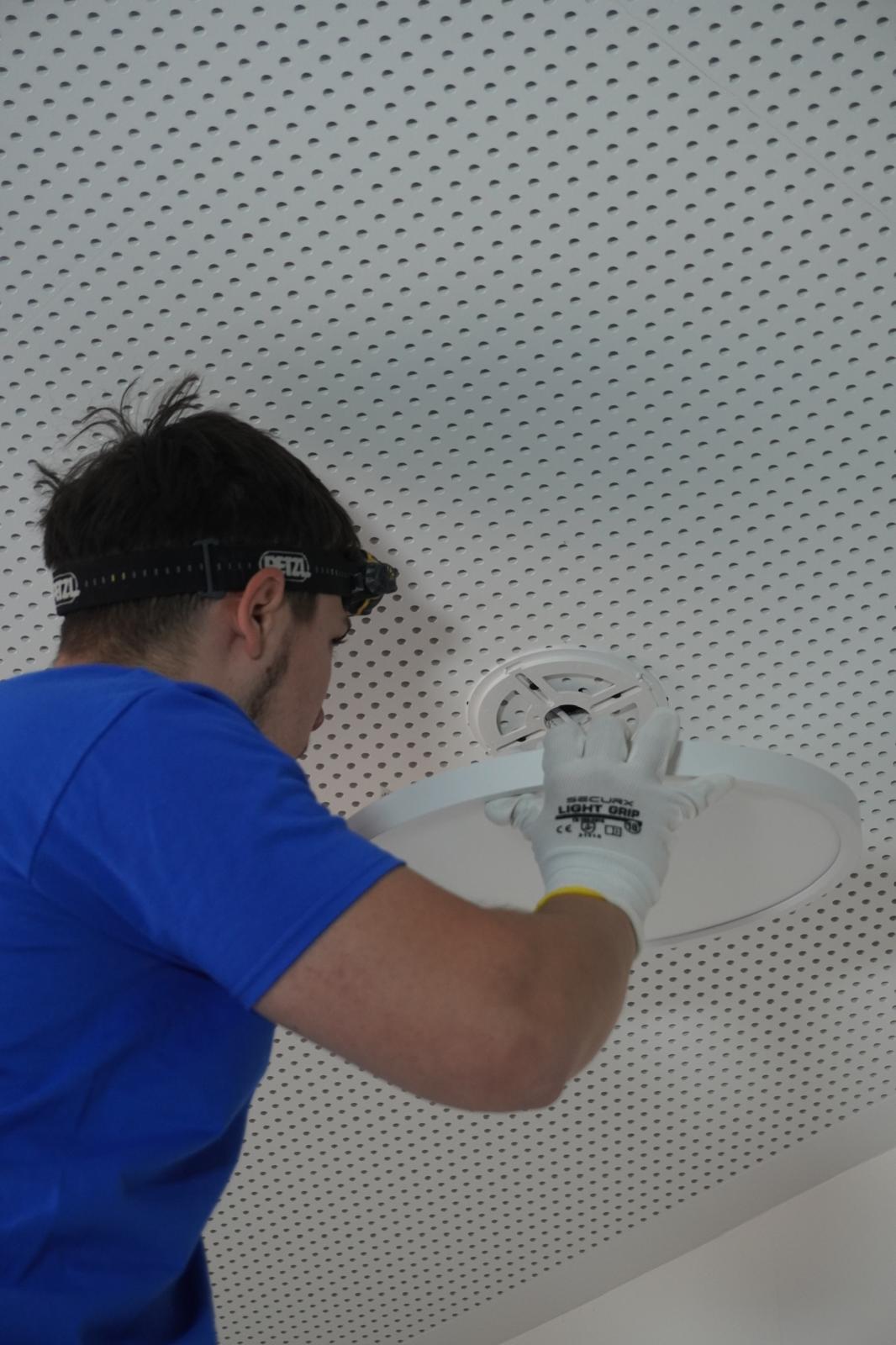 Technicien ADY ART installant un spot au plafond perforé