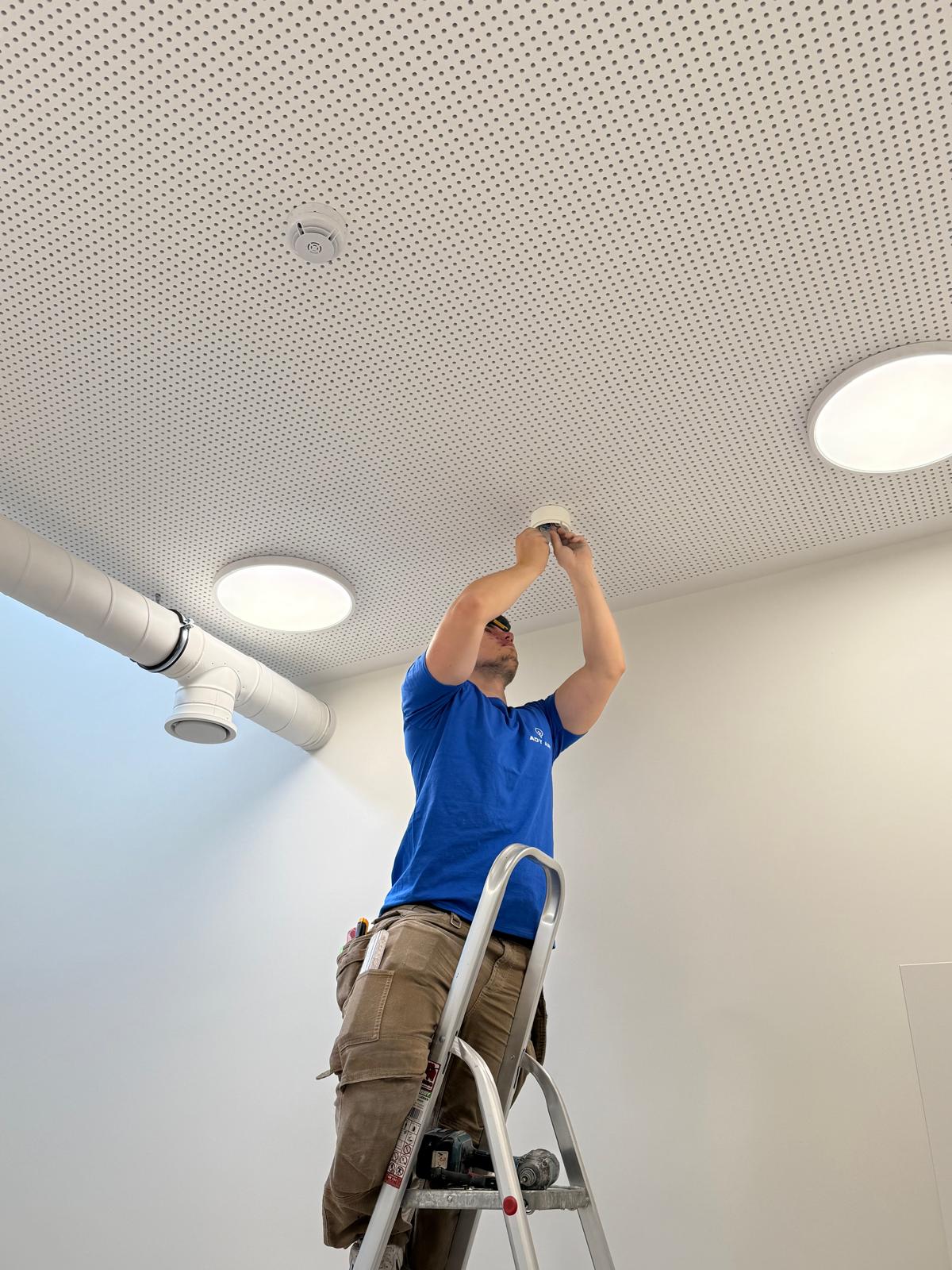 Technicien ADY ART sur échelle installant un spot LED