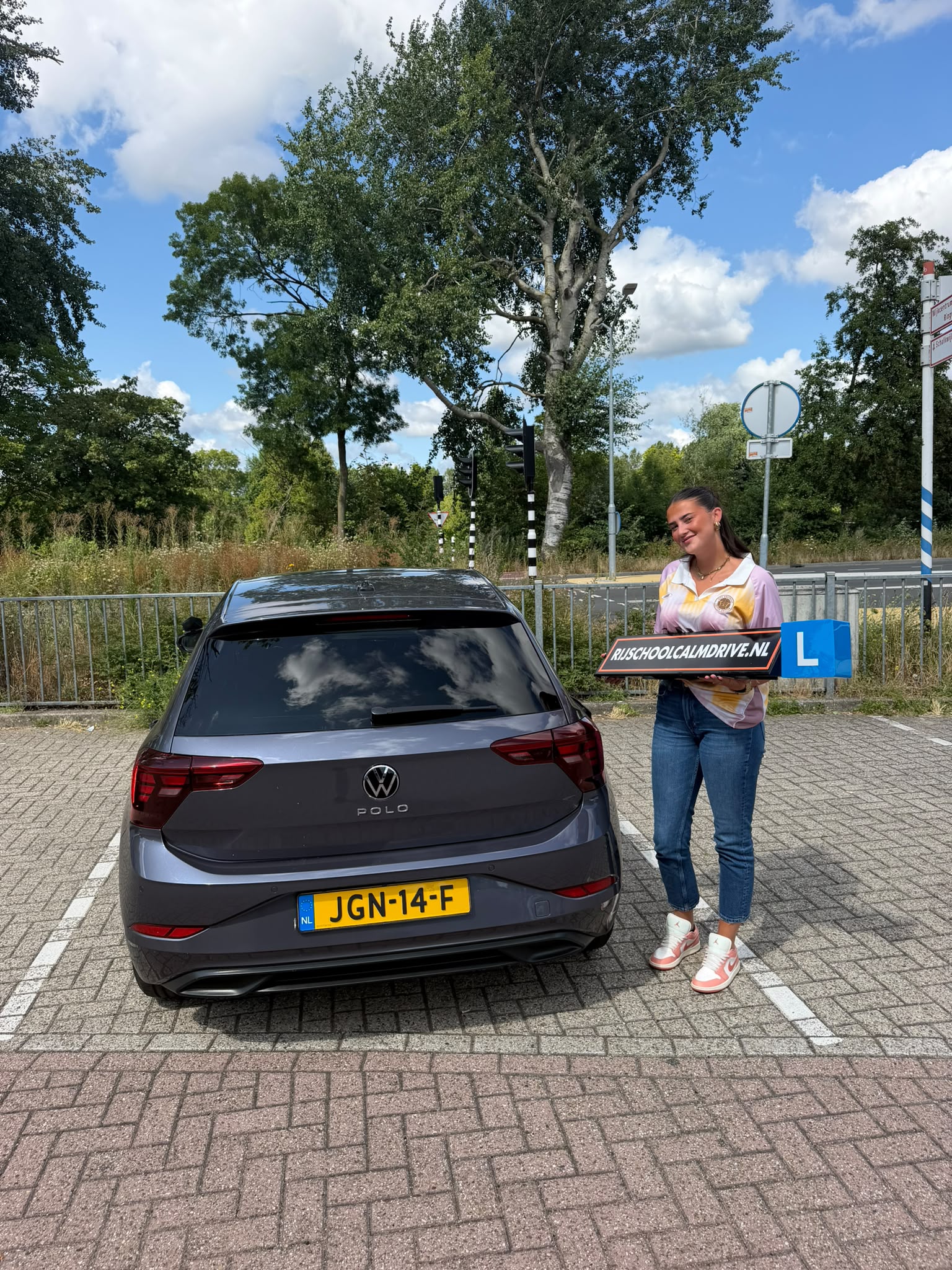 Geslaagde leerling bij witte Calm Drive lesauto