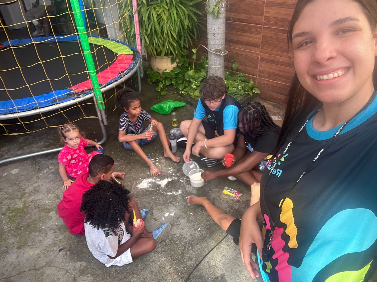 Recreadora da RecriaKids com um grupo de crianças fazendo oficina de slime ao ar livre