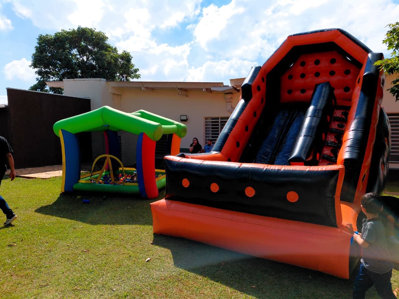 Piscina de bolinhas colorida ao lado de um tobogã inflável laranja e preto