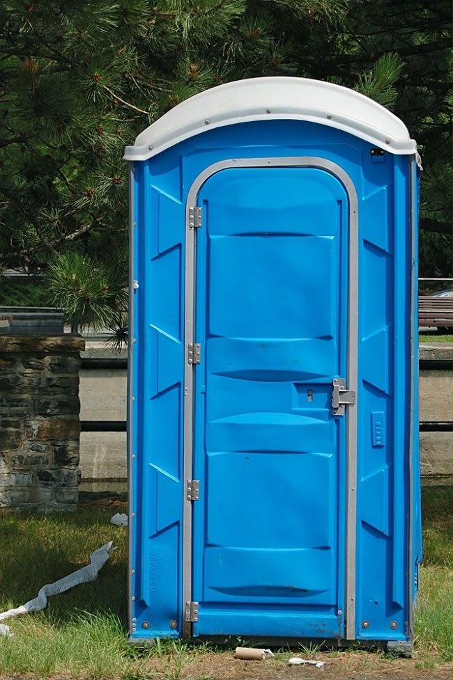 Blue portable restroom outdoors near a residential property