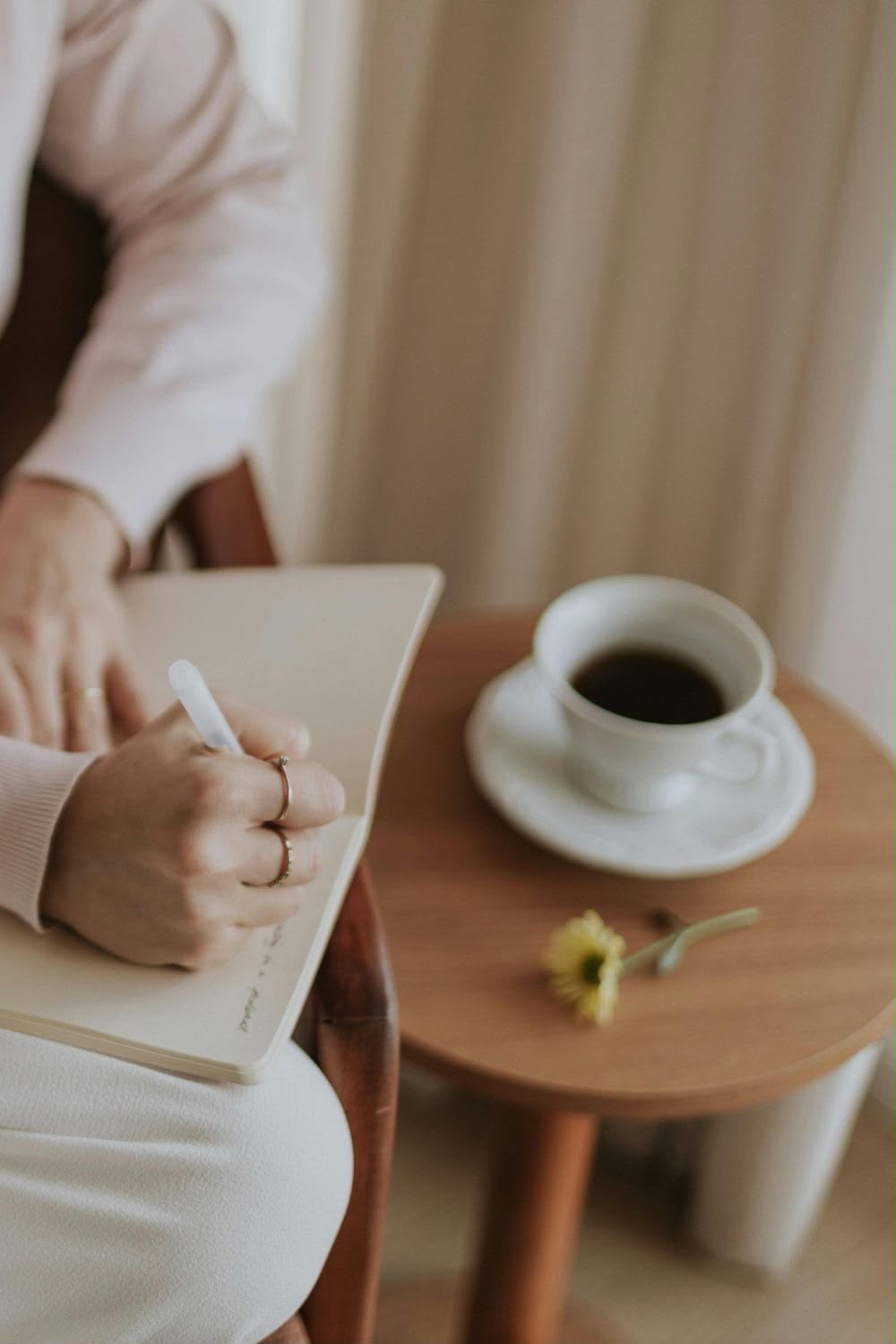 Pessoa escrevendo em um caderno ao lado de uma xícara de café