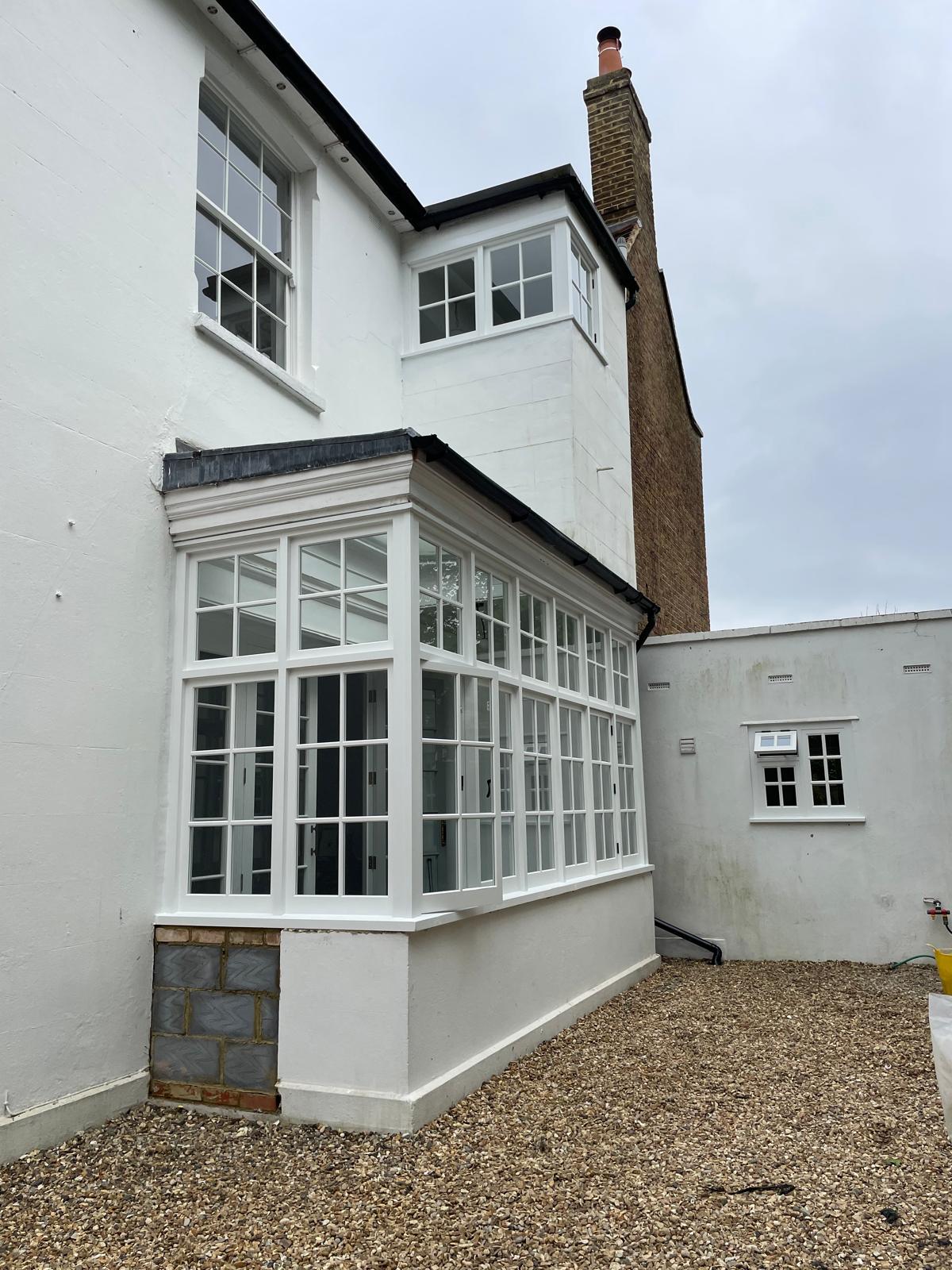 Restored white timber box bay sash windows on a period property
