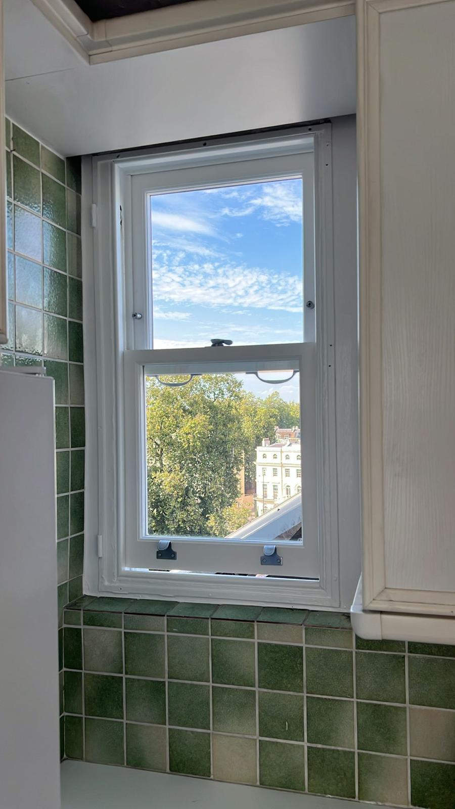 Restored white sash window above a green-tiled kitchen surface