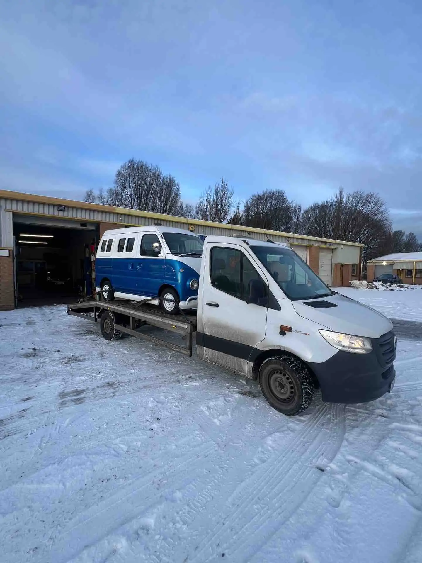 SCR Recovery flatbed truck transporting a classic blue campervan in winter