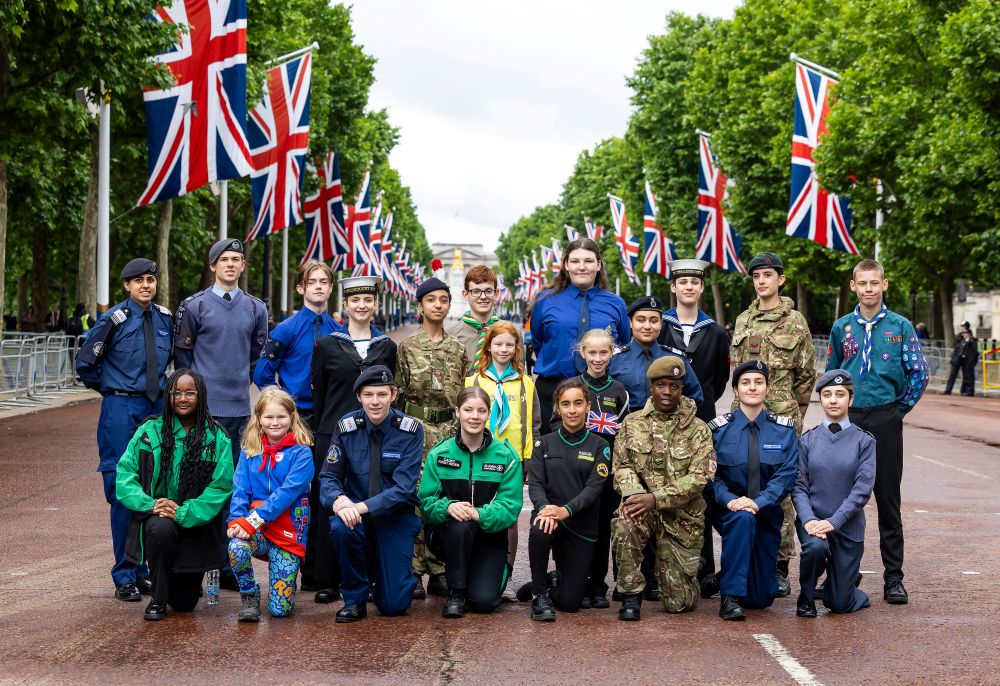 Young people from YOU London partner organisations in uniform on The Mall, with Union Jack flags lining the avenue toward Buckingham Palace.