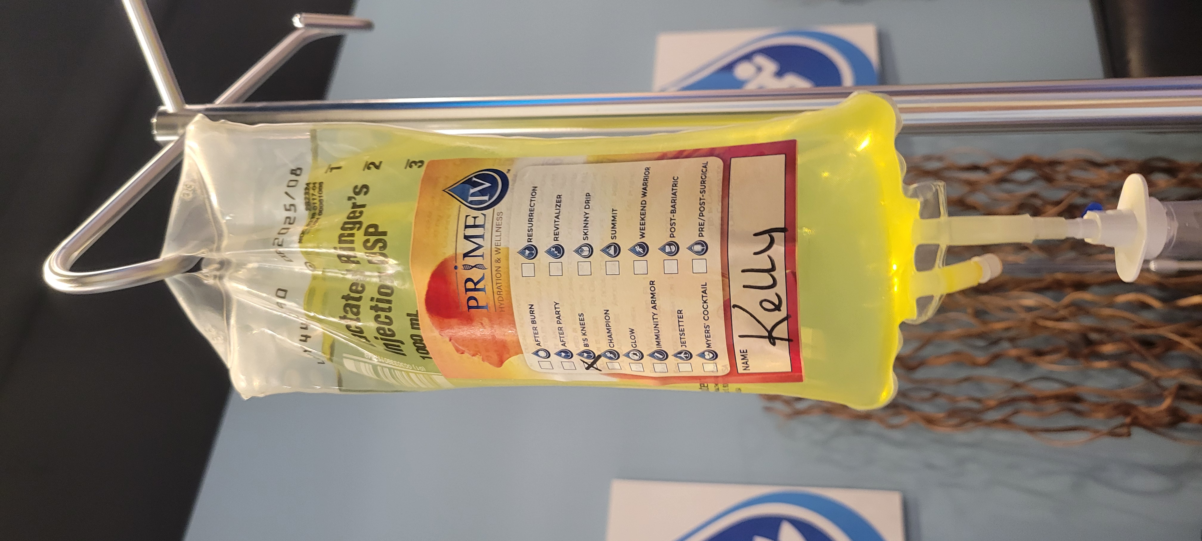Close-up of a personalized Prime IV drip bag with a bright yellow infusion labeled for a client