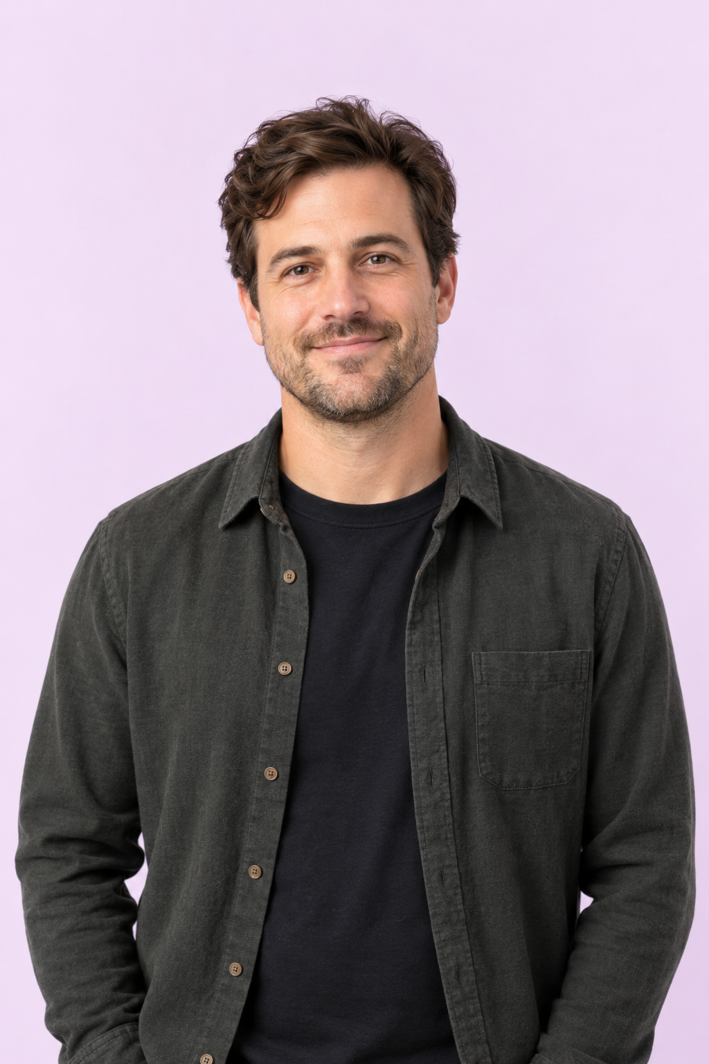Zach Primavera smiling in a charcoal overshirt against a pale lavender background