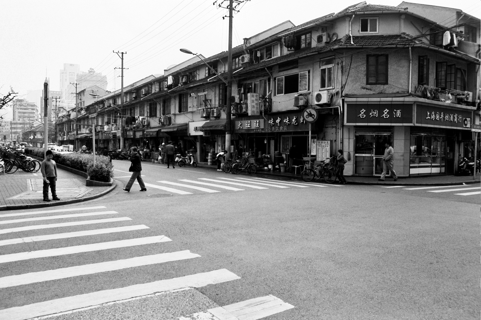 Shanghai street intersection with pedestrians and traditional shophouses with Chinese signage