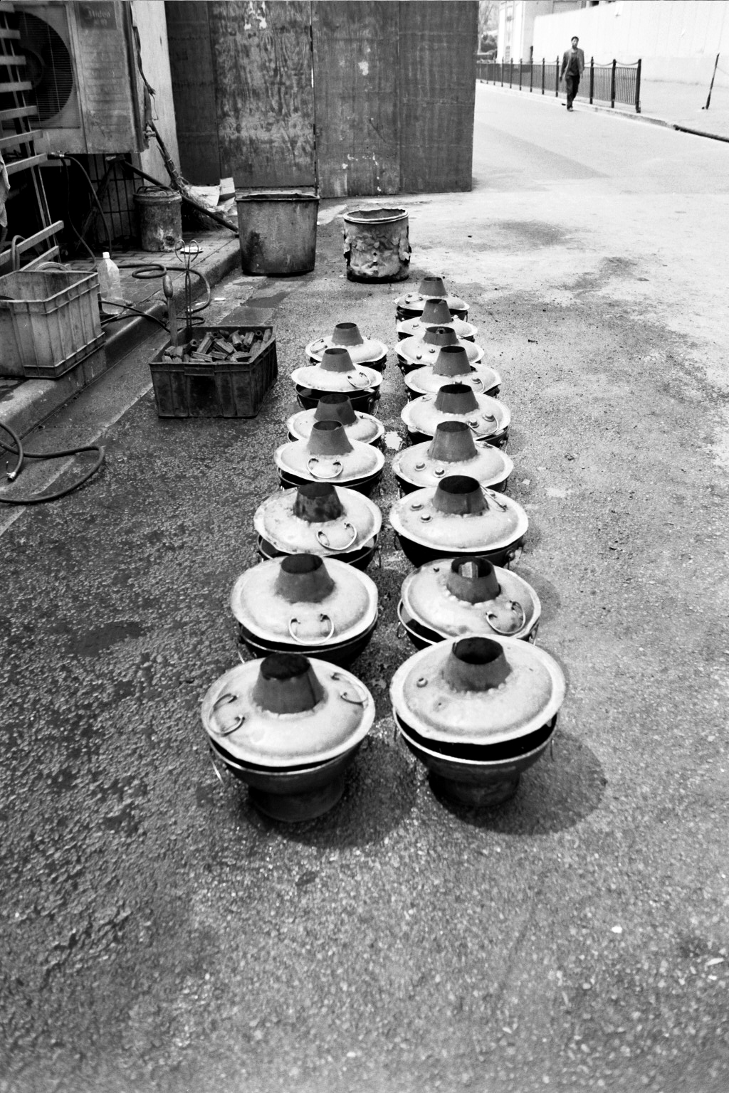 Rows of traditional metal cooking pots with conical lids on street