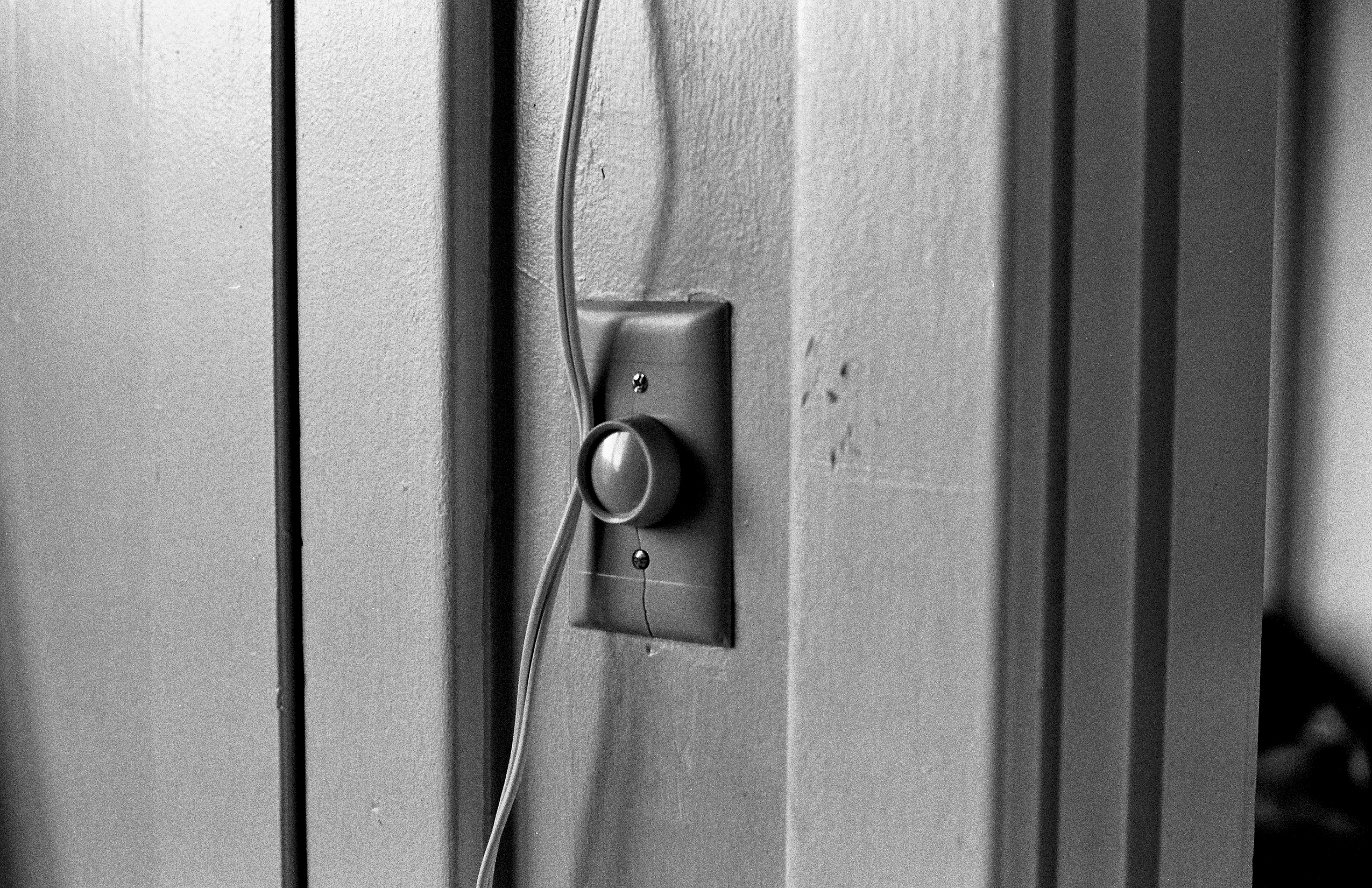 Dimmer switch on textured wall with electrical wire creating shadow patterns in architectural detail